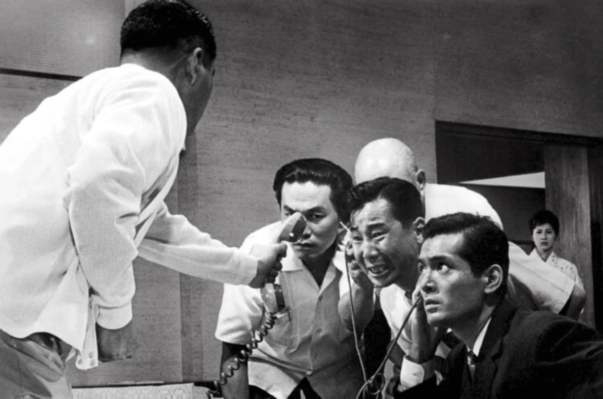 Hombres angustiados escuchando una llamada telefónica en una escena del thriller japonés El Infierno del Odio (1963) de Akira Kurosawa